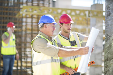 Construction workers discussing building plans in construction site - ZEF001604