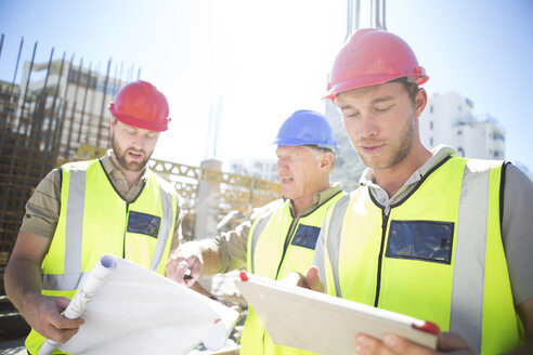 Drei Bauarbeiter mit digitalem Tablet auf einer Baustelle - ZEF001595