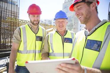 Drei Bauarbeiter mit digitalem Tablet auf einer Baustelle - ZEF001596