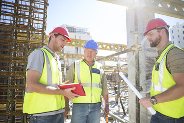 Drei Bauarbeiter unterhalten sich auf einer Baustelle - ZEF001600