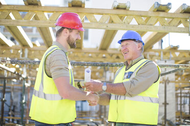 Two construction workers shaking hands in construction site - ZEF001632