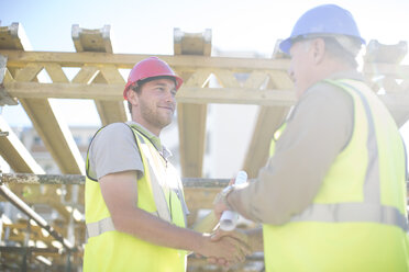 Two construction workers shaking hands in construction site - ZEF001634