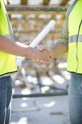 Two construction workers shaking hands in construction site - ZEF001646