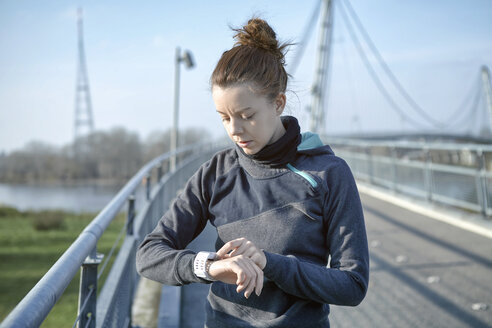 Junge Frau, die nach dem Joggen ihren Pulsmesser überprüft - SEGF000069