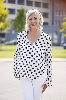 Porträt einer lächelnden älteren Frau in weißer Bluse mit schwarzen Punkten - VRF000127