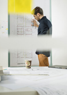 Junger Architekt im Büro bei der Arbeit an einem Bauplan - UUF002778