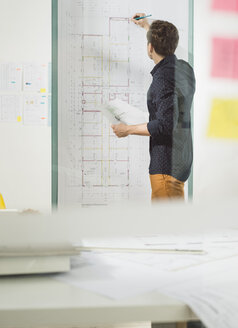 Junger Architekt im Büro bei der Arbeit an einem Bauplan - UUF002779