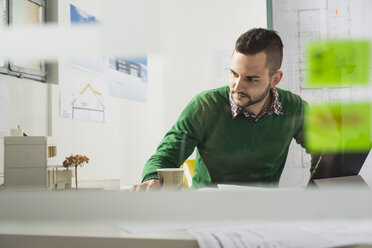 Young man at desk looking at architectural model - UUF002786