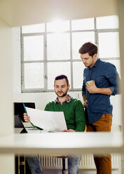 Two young men in office discussing document - UUF002790