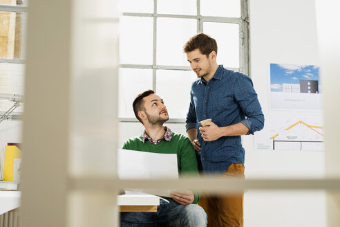 Zwei junge Männer im Büro besprechen ein Dokument - UUF002791