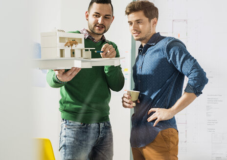 Zwei junge Architekten diskutieren in einem Büro über ein Architekturmodell - UUF002795