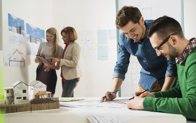 Junge Architekten im Büro beim Betrachten eines Bauplans - UUF002814