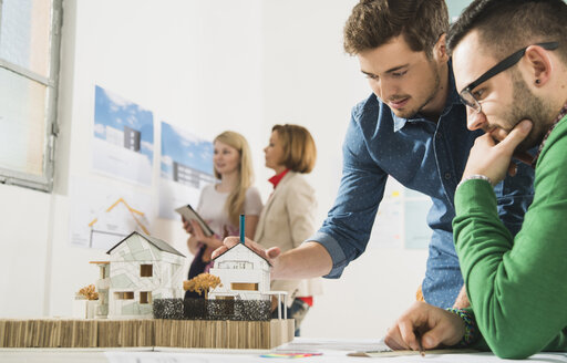 Junge Architekten im Büro beim Betrachten eines Architekturmodells - UUF002815