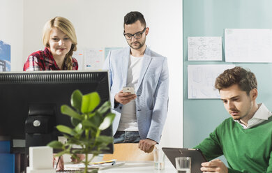 Drei junge Leute im Büro mit Computermonitor - UUF002832