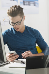 Young man at desk with computer and cell phone - UUF002846