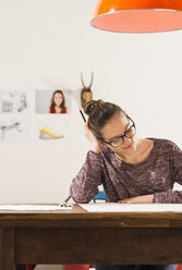 Young woman looking at her drawing at home - UUF002733