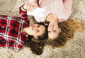 Zwei Freundinnen machen ein Selfie mit dem Smartphone zu Hause - UUF002756