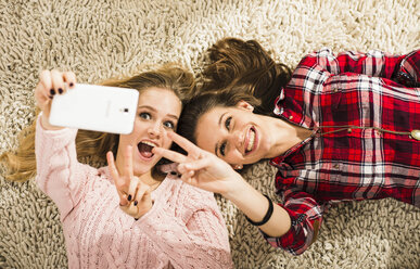 Zwei Freundinnen machen ein Selfie mit dem Smartphone zu Hause - UUF002759
