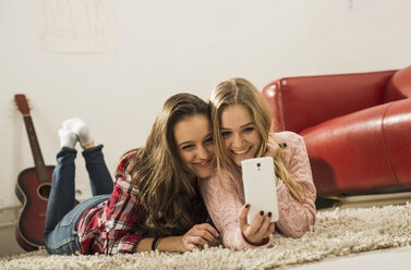 Zwei Freundinnen machen ein Selfie mit dem Smartphone zu Hause - UUF002744