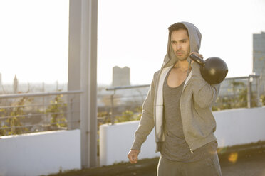 Mann in Kapuzenjacke trainiert mit Kettlebell - MAD000116