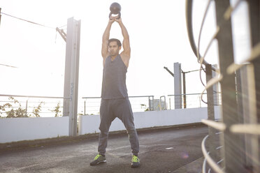 Mann trainiert mit Kettlebell bei Gegenlicht - MAD000118