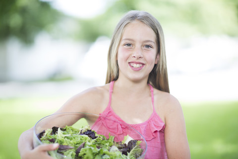 Porträt eines lächelnden Mädchens, das eine Schüssel mit Salat hält, lizenzfreies Stockfoto