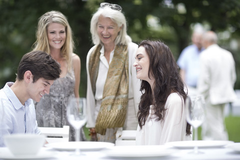 Glückliche Familie, die sich um einen Tisch im Garten versammelt, lizenzfreies Stockfoto