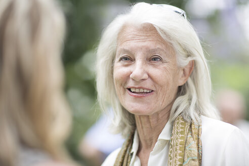 Lächelnde ältere Frau bei einem Gespräch im Freien - ZEF003456