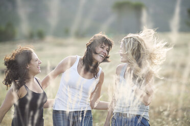 South Africa, Girl friends dancing and jumping in field - ZEF002772