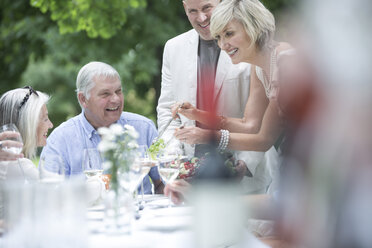 Woman dishing up salad on a garden party - ZEF003465