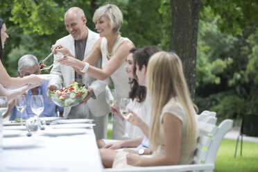 Woman dishing up salad on a garden party - ZEF003466