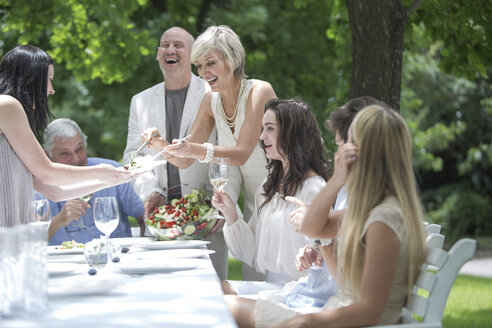 Frau tischt Salat auf einer Gartenparty auf - ZEF003467