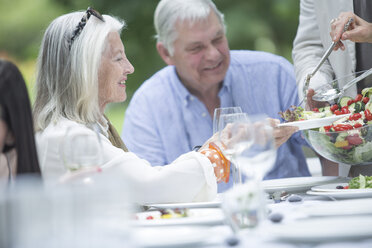 Frau tischt Salat auf einer Gartenparty auf - ZEF003468