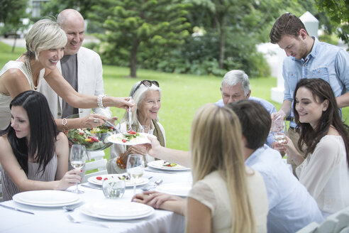 Frau tischt Salat auf einer Gartenparty auf - ZEF003470