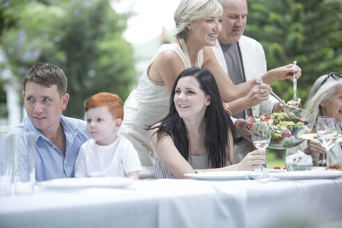 Frau tischt Salat auf einer Gartenparty auf - ZEF003471