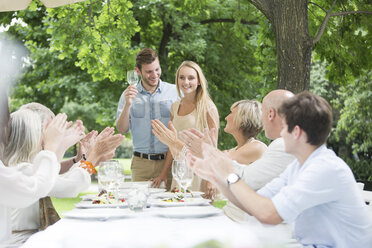 Menschen klatschen in die Hände für ein junges Paar auf einer Gartenparty - ZEF003474