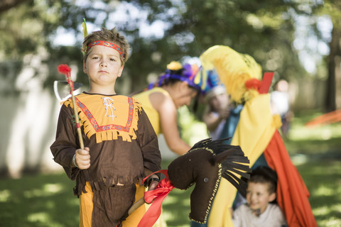 Porträt eines Jungen im Garten, der Cowboy und Indianer spielt, lizenzfreies Stockfoto