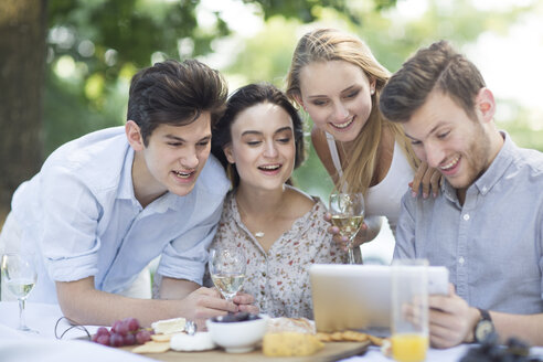 Freunde essen im Freien und benutzen ein digitales Tablet - ZEF003508