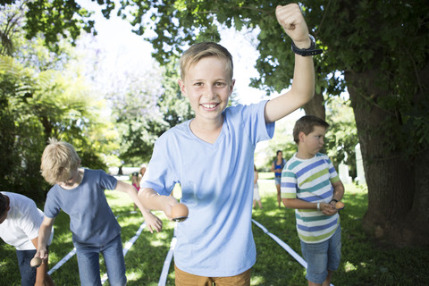 Junge gewinnt beim Wettlauf mit Ei und Löffel, lizenzfreies Stockfoto