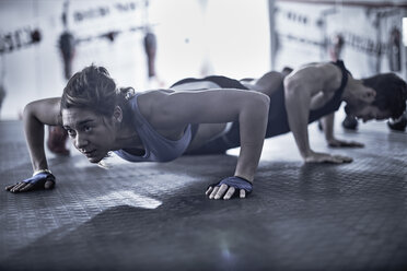 Man and woman doing push-ups in gym - ZEF002622