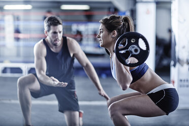 Trainer beobachtet Frau beim Fitnesstraining mit Gewichten - ZEF002627