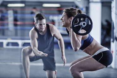Trainer beobachtet Frau beim Fitnesstraining mit Gewichten - ZEF002628