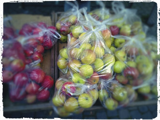 Apples in plastic bags at market stall - MYF000757