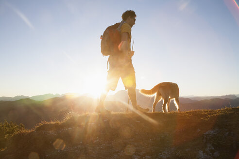 Österreich, Tirol, Unterberghorn, Wanderer mit Hund bei Sonnenaufgang - RBF002098