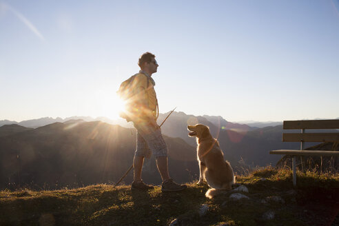 Österreich, Tirol, Unterberghorn, Wanderer mit Hund bei Sonnenaufgang - RBF002099