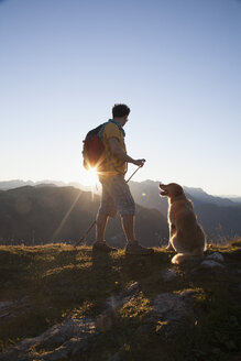 Österreich, Tirol, Unterberghorn, Wanderer mit Hund bei Sonnenaufgang - RBF002100