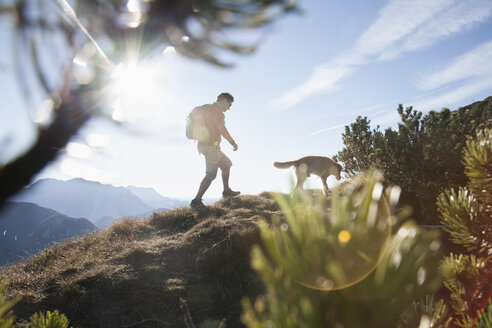 Österreich, Tirol, Unterberghorn, Wanderer mit Hund bei Sonnenaufgang - RBF002097