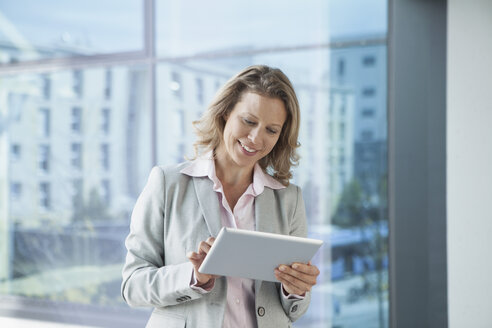 Lächelnde Geschäftsfrau mit digitalem Tablet im Büro - RBF002116