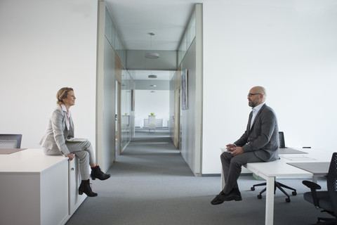 Zwei Kollegen sitzen auf dem Büroboden, lizenzfreies Stockfoto