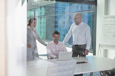 Three businesspeople with laptop in conference room - RBF002160